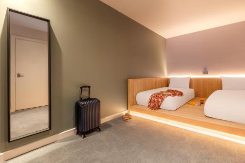 ein Schlafzimmer mit 2 Betten, einem Spiegel und einem Koffer in der Unterkunft Zedwell Greenwich in London