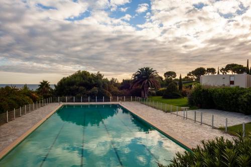 - une piscine dans une cour avec un ciel nuageux dans l'établissement Vue Mer Dans Belle Résidence, à Cassis