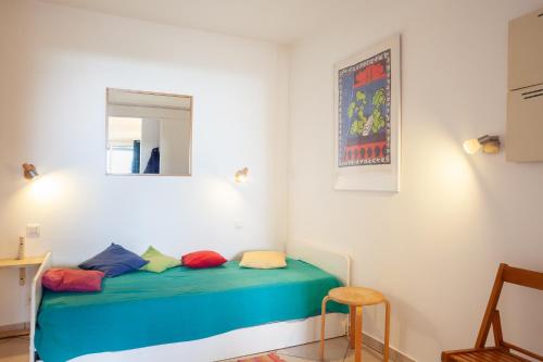 Cette chambre comprend un lit avec des oreillers colorés. dans l'établissement Vue Mer Dans Belle Résidence, à Cassis