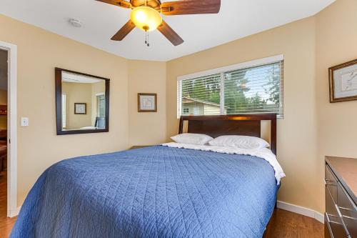 a bedroom with a blue bed with a ceiling fan at Summit Lake Guesthouse in Kamilche