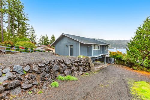 a blue house with a stone wall next to a road at Summit Lake Guesthouse in Kamilche