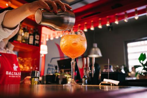 a person pours a drink into a glass on a bar at BALTAZÁR Boutique Hotel in Budapest