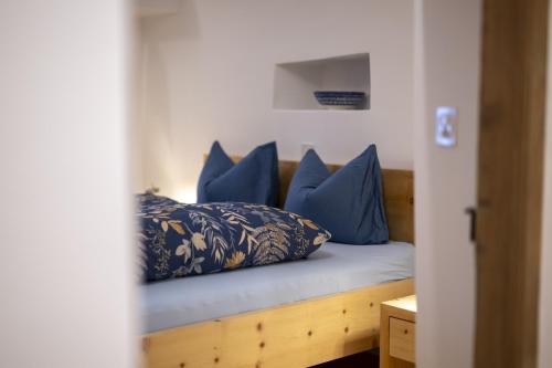 a bed with blue pillows on top of it at Chasa Bijou in Ftan