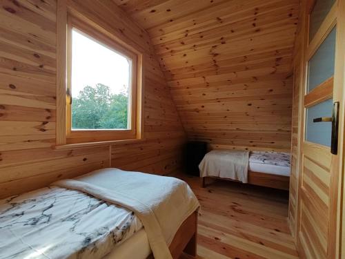 Blockhausschlafzimmer mit einem Bett und einem Fenster in der Unterkunft BAJKA-Domek na wsi in Domaszków