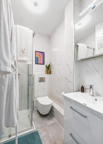 a white bathroom with a shower and a toilet at Bella Luna Luxury Suites - Oasis Gem Near Stadium & Old Town in Warsaw