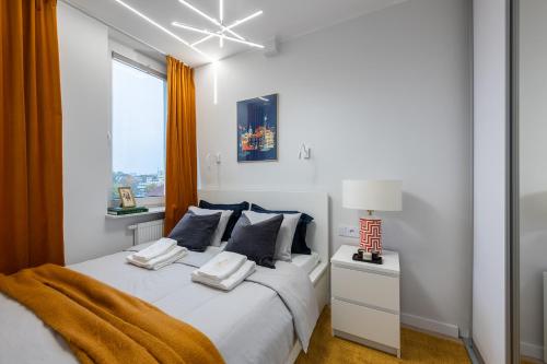a white bedroom with a large bed with blue pillows at Bella Luna Luxury Suites - Oasis Gem Near Stadium & Old Town in Warsaw