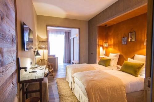 a hotel room with two beds and a desk at Hôtel de la Roche in Beaufort