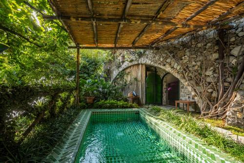 an outdoor swimming pool in a garden with a stone wall at Villa Treville in Positano