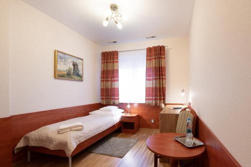 1 dormitorio con cama, mesa y ventana en Hotel Reśliński, en Grodzisk Wielkopolski