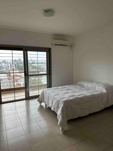 een witte slaapkamer met een bed en een groot raam bij Departamento en Merlo Centro in Merlo