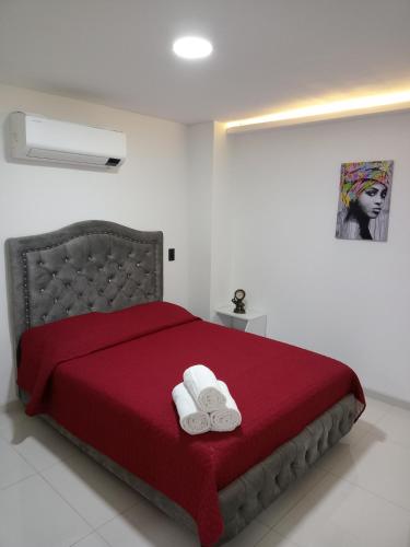una camera con un letto rosso e due asciugamani bianchi di Apartamento cerca al Centro comercial Nuestro Cartago a Cartago