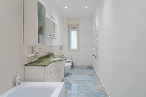 a white bathroom with a sink and a toilet at Bedda in Siracusa
