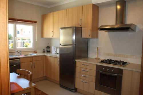 uma cozinha com armários de madeira e um frigorífico de aço inoxidável em 4 bedroom town house Vale de Parra, close to Gale AT22 na Guia