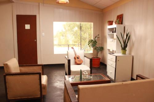 ein Wohnzimmer mit einer Gitarre auf einem Stuhl in der Unterkunft La Cabaña de Susy in Los Baños del Inca