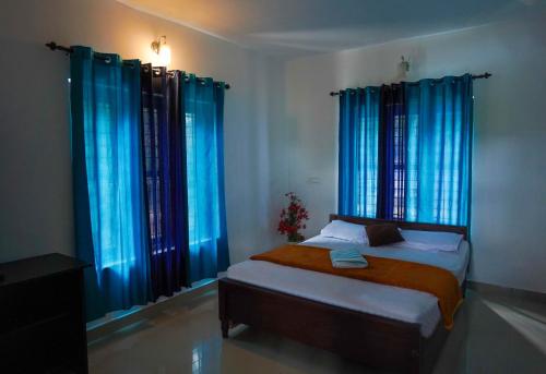 1 dormitorio con cortinas azules y 1 cama en una habitación en Karapuzha Homestay, en Meenangadi