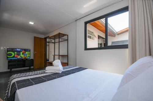 Un dormitorio con una cama y un televisor y una ventana. en 12 Hóspedes - Piscina Àgua Salgada e Área Gourmet, en Foz do Iguaçu