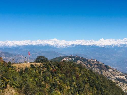a flag on top of a hill with snow covered mountains at Nagarkot Trekkers Inn in Nagarkot
