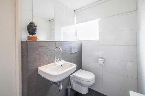 a white bathroom with a sink and a toilet at Museumpark Apartments in Rotterdam