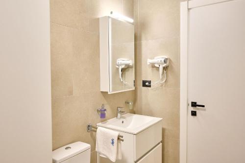 a bathroom with a sink and a toilet and a mirror at Mara Sea View Apartment in Năvodari