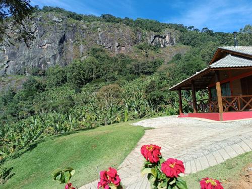 een gebouw met rode bloemen voor een berg bij Chalé da Sorte in Gonçalves