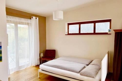 um quarto com uma cama com uma janela e uma cadeira em Bioappartement mit Garten, Waldnähe, Blick ins Inntal 100m em Simbach am Inn