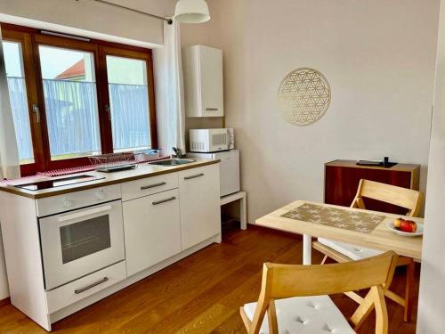 een keuken met witte apparatuur en een tafel met stoelen bij Bioappartement mit Garten, Waldnähe, Blick ins Inntal 100m in Simbach am Inn