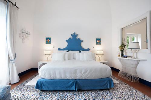 a bedroom with a large bed with a blue headboard at Villa Treville in Positano