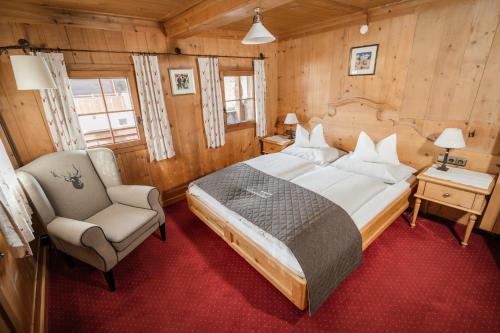 a bedroom with a large bed and a chair at Gästehaus Leirerhäusl in Alpbach