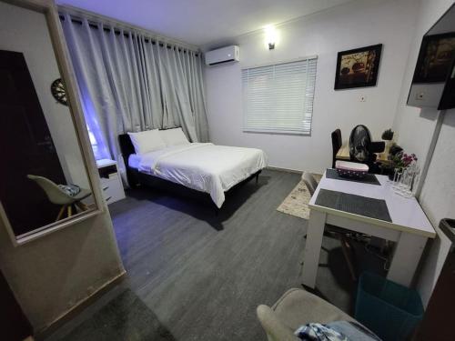 1 dormitorio con 1 cama y escritorio en una habitación en Sonia Apartments Ikeja, en Lagos