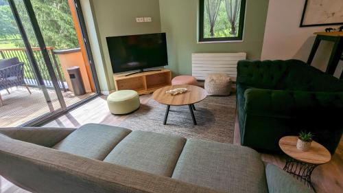 ein Wohnzimmer mit einem Sofa und einem TV in der Unterkunft Hostel des Combes in Les Combes
