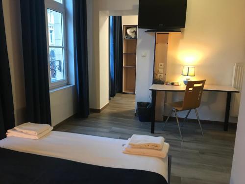 um quarto com uma cama, uma secretária e uma cadeira em Cesar Hotel em Charleville-Mézières