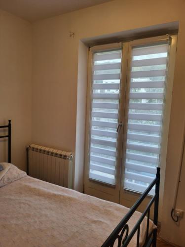 a bedroom with a bed and a window with shutters at Apartman LAZAR I VIKTOR in Vrnjačka Banja
