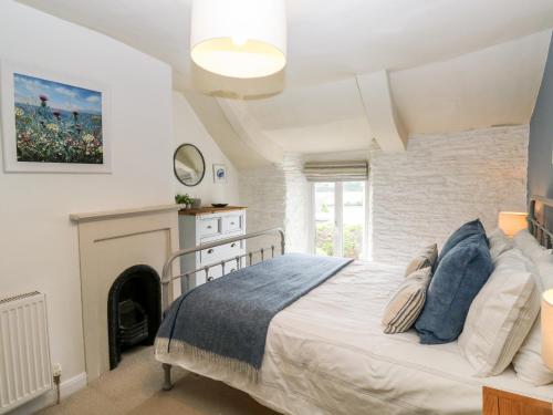 um quarto com uma cama e uma lareira em Alexander's Cottage em Kingsbridge
