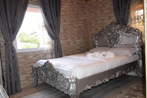 1 dormitorio con cama ornamentada y ventana en Ghazalle oasis Hotel GB, en El Biar