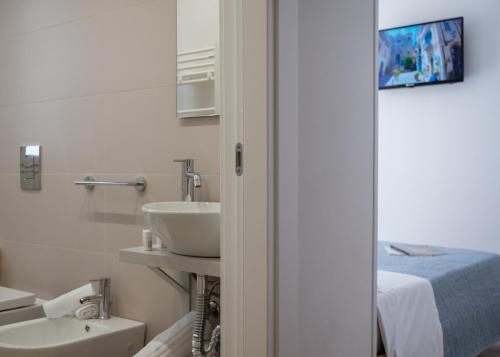 a small bathroom with a sink and a bed at Incanto B&B Cefalù in Cefalù