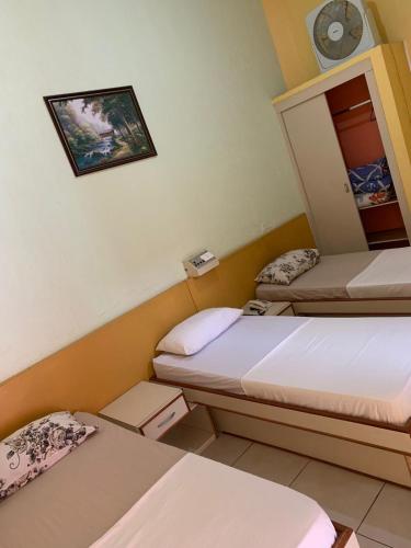 a room with two beds and a clock on the wall at Hotel Mooca in Sao Paulo