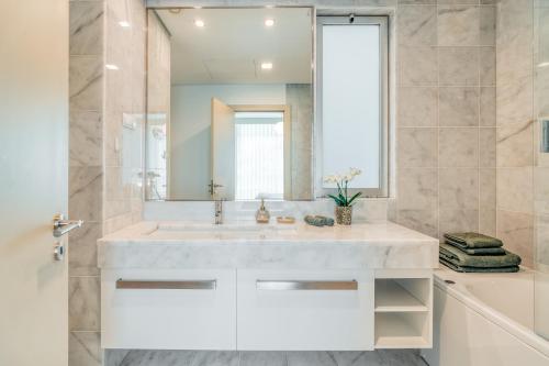 uma casa de banho com um lavatório branco e um espelho. em Royal Sea View III no Funchal