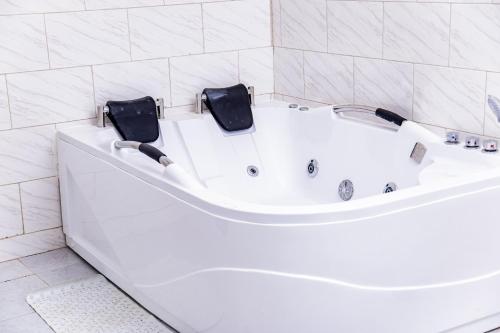 La salle de bains est pourvue d'une baignoire blanche et de carrelage blanc. dans l'établissement PINORICH VILLA-Buea, à Buea