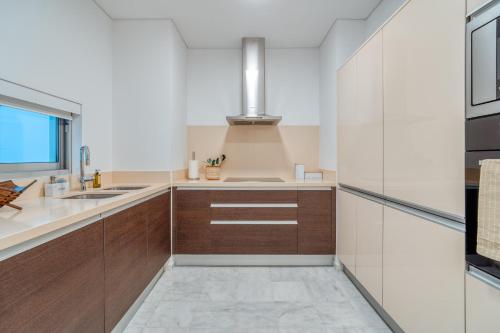a kitchen with wooden cabinets and a sink at Suite CU - Sea View - 3 Pools - AC - Free Park - Free Gym in Funchal