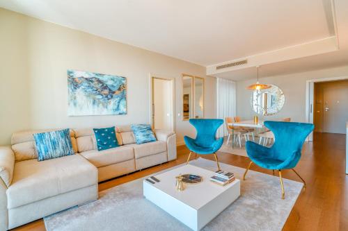 a living room with a couch and blue chairs at Suite CU - Sea View - 3 Pools - AC - Free Park - Free Gym in Funchal