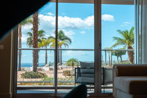 a living room with a view of the ocean and palm trees at Suite CU - Sea View - 3 Pools - AC - Free Park - Free Gym in Funchal