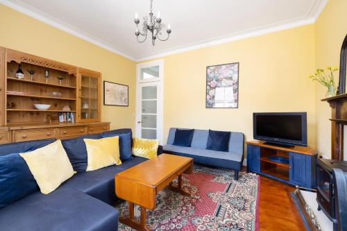 a living room with a blue couch and a tv at Edinburgh Holyrood Park Views Apartment in Edinburgh