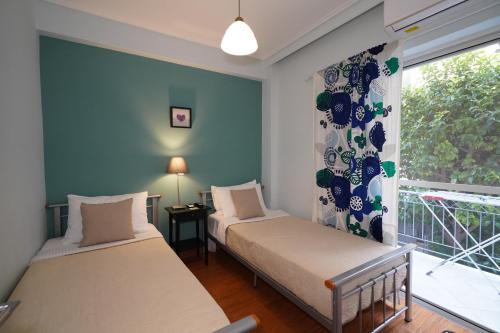 two beds in a room with a window at Garden Apartment next to the Mall -Private Parking in Athens