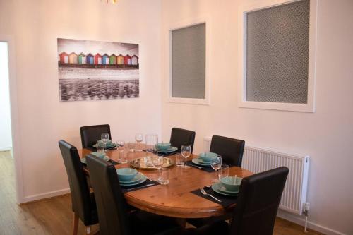 uma sala de jantar com uma mesa de madeira e cadeiras em Dolce Central Lord St. Flat 1 em Southport