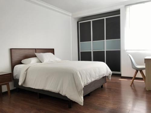 a white bedroom with a large bed and a chair at Condesa Residence Campeche 11 Exceptional 2BR, 1BA Apartment with Grand Living Space in Mexico City