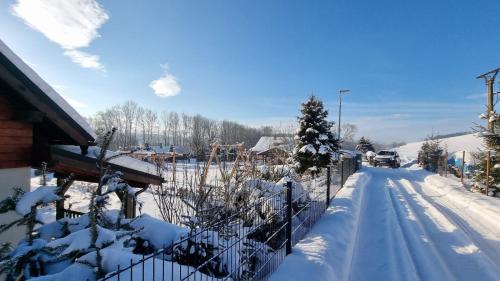 a fence covered in snow next to a house at Evin*raj in Kvačany