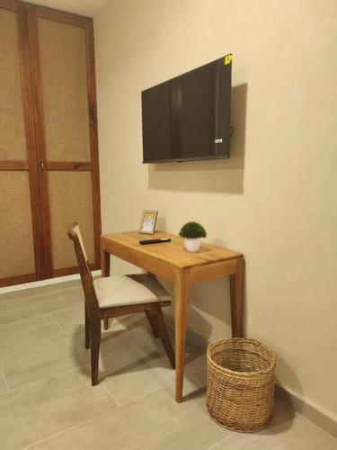 a desk with a chair and a television on a wall at Comfortable private apartment AC near Montejo - Las Huayitas in Mérida