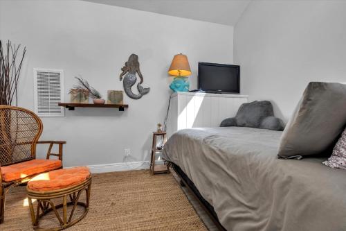 a bedroom with a bed and a chair and a tv at Sneaky Tiki: Heated Saltwater Pool+5 min to beach in Largo
