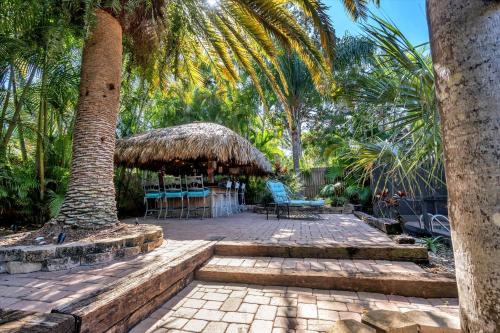 a patio with a palm tree and a table and chairs at Sneaky Tiki: Heated Saltwater Pool+5 min to beach in Largo