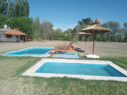 una piscina con sombrilla, mesa y sillas en CABAÑAS LA PILARICA en San Rafael